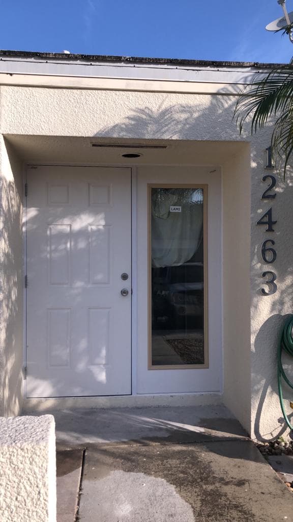 On-site photo showing impact window frame being installed into a Florida home wall opening with level and measurement tools